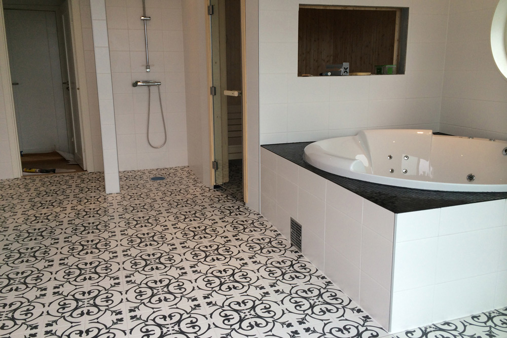 Badrum med mönstrat klinkergolv, dusch och inbyggt hörnbadkar